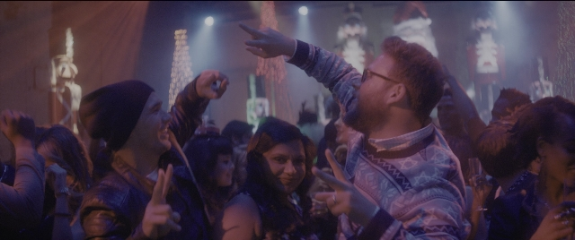 Wide shot frame from The Night Before — room, hand, shirt