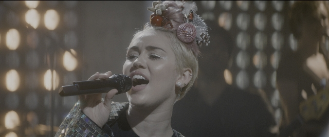Wide shot frame from The Night Before — microphone, hair, person