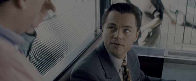 Medium shot frame from The Wolf of Wall Street — sitting, suit, tie