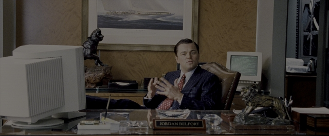 Wide shot frame from The Wolf of Wall Street — sitting, desk, dog
