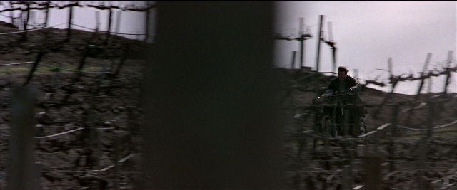 Wide shot frame from Black Rain — sitting, hat, bicycle