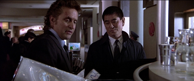 Wide shot frame from Black Rain — table, fire, suit
