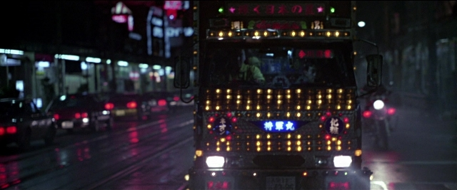 Wide shot frame from Black Rain — street, night, bus