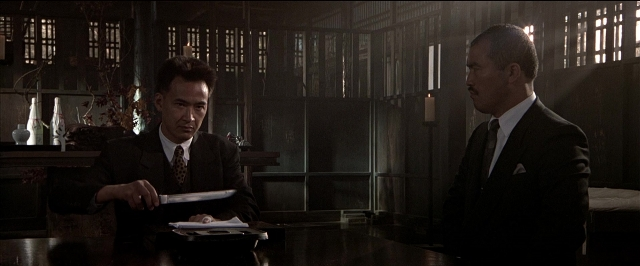 Wide shot frame from Black Rain — standing, room, table