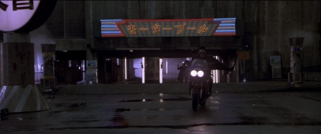 Wide shot frame from Black Rain — street, water, wheel