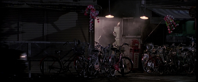 Wide shot frame from Black Rain — night, bicycle, bicycle wheel