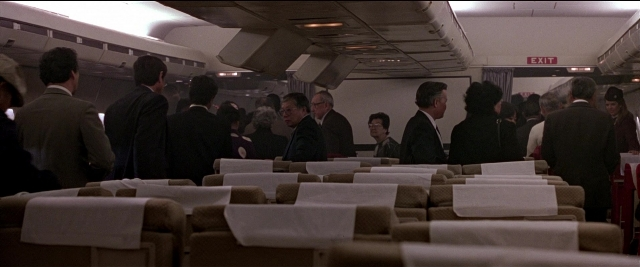 Wide shot frame from Black Rain — sitting, standing, suit