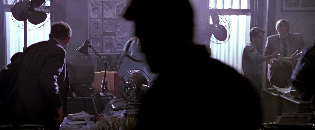 Wide shot frame from Black Rain — standing, room, hat