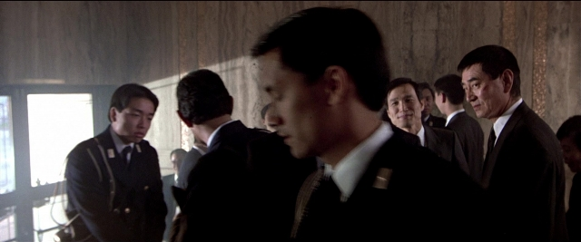 Wide shot frame from Black Rain — standing, room, suit