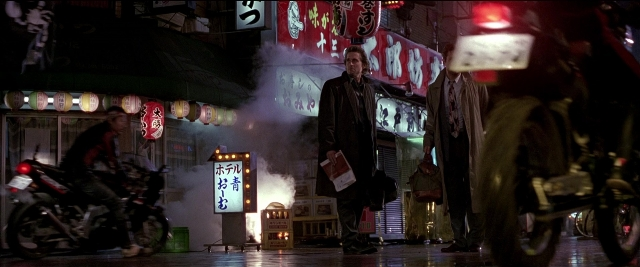 Wide shot frame from Black Rain — sitting, standing, street