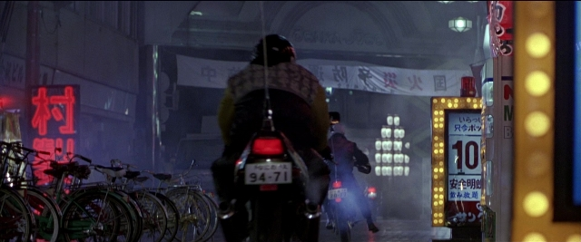 Wide shot frame from Black Rain — plate, street, hat