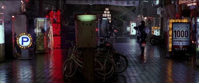 Wide shot frame from Black Rain — street, night, bicycle