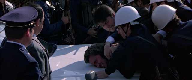 Frame from Black Rain — sitting, standing, person