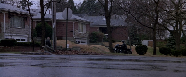 Wide shot frame from Black Rain — street, house, person