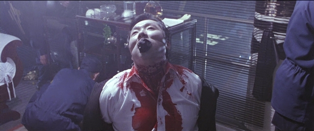 Frame from Black Rain — standing, room, table