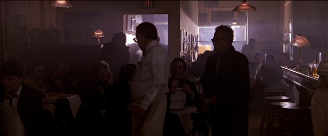Wide shot frame from Black Rain — sitting, standing, table