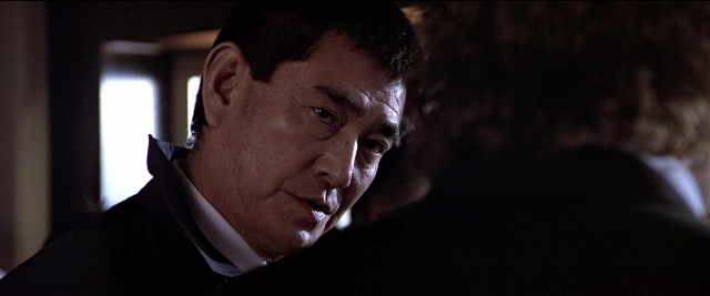 Wide shot frame from Black Rain — room, suit, tie