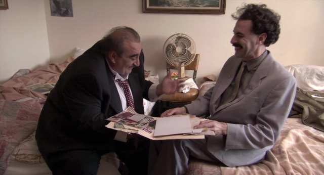 Wide shot frame from Borat: Cultural Learnings of America for Make Benefit Glorious Nation of Kazakhstan — sitting, bed, suit