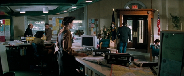 Wide shot frame from In the Mouth of Madness — sitting, desk, book