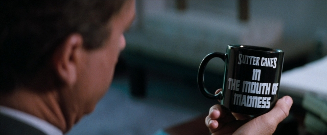 Wide shot frame from In the Mouth of Madness — room, suit, face