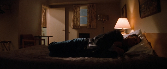 Frame from In the Mouth of Madness — room, table, bed