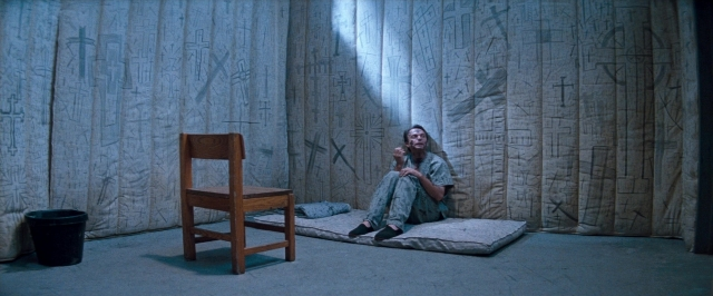 Wide shot frame from In the Mouth of Madness — sitting, room, bed