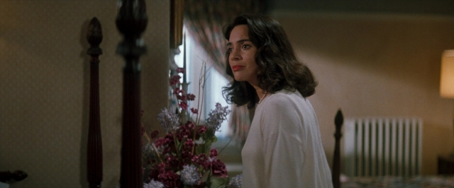 Wide shot frame from In the Mouth of Madness — standing, room, bed