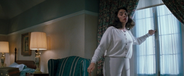 Wide shot frame from In the Mouth of Madness — standing, room, bed