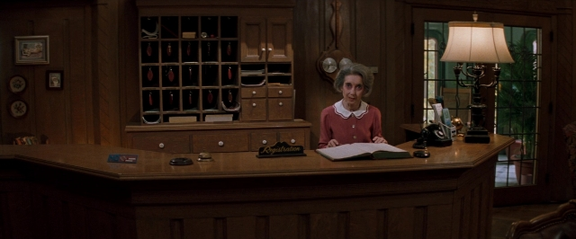 Wide shot frame from In the Mouth of Madness — sitting, desk, room