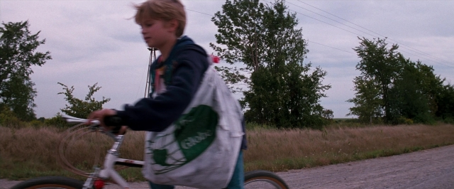 Frame from In the Mouth of Madness — street, bicycle, face