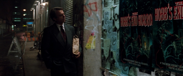 Wide shot frame from In the Mouth of Madness — walking, street, hand