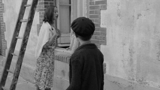 Wide shot frame from In the Mouth of Madness — standing, dress, face
