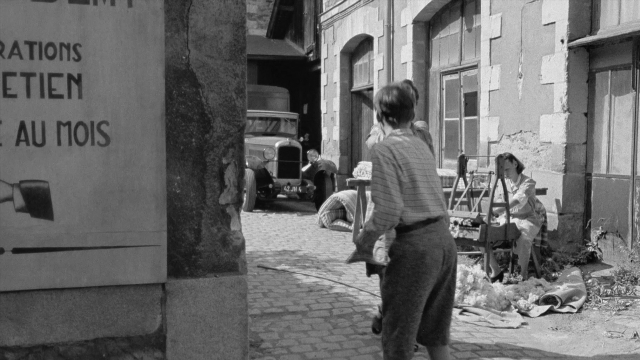 Wide shot frame from In the Mouth of Madness — people, sitting, action