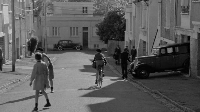 Wide shot frame from In the Mouth of Madness — walking, street, hat