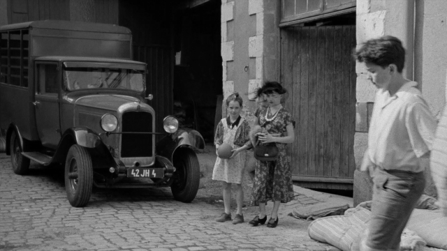 Wide shot frame from In the Mouth of Madness — standing, door, street