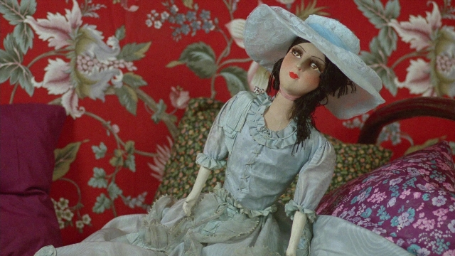 Wide shot frame from In the Mouth of Madness — sitting, bed, hat