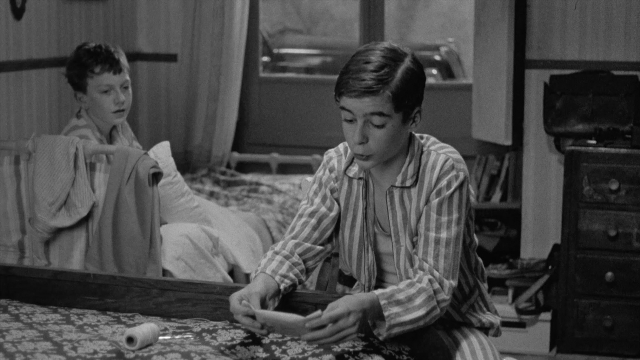 Wide shot frame from In the Mouth of Madness — sitting, room, bed