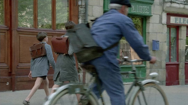 Wide shot frame from In the Mouth of Madness — walking, street, hat