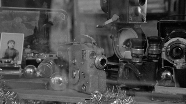 Wide shot frame from In the Mouth of Madness — room, table, suit