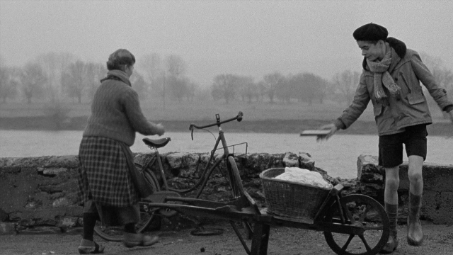Wide shot frame from In the Mouth of Madness — standing, dialogue, hat