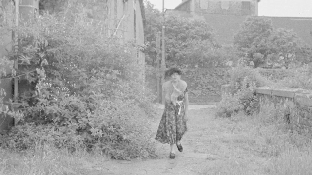 Wide shot frame from In the Mouth of Madness — walking, hat, hand