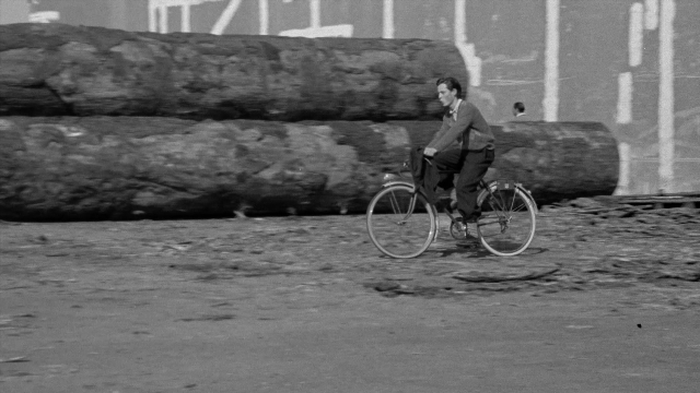 Wide shot frame from In the Mouth of Madness — sitting, suit, tie