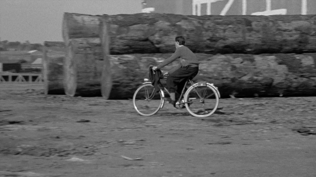Frame from In the Mouth of Madness — suit, tie, bicycle