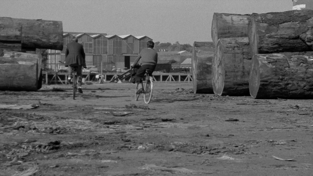 Wide shot frame from In the Mouth of Madness — street, bicycle, person