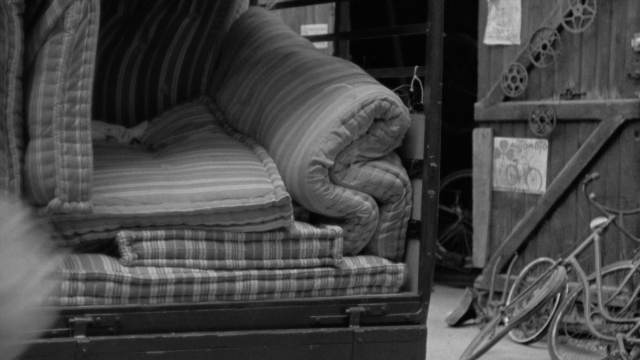 Wide shot frame from In the Mouth of Madness — bicycle, furniture, wheel