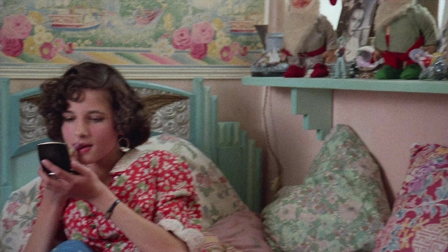Wide shot frame from In the Mouth of Madness — sitting, bed, phone