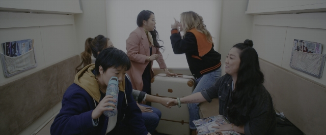 Wide shot frame from Joy Ride — sitting, standing, room