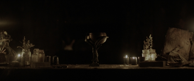 Wide shot frame from The Conjuring: The Devil Made Me Do It — table, bird, candle