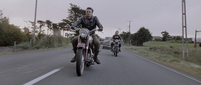 Wide shot frame from The World's Fastest Indian — street, car, bicycle
