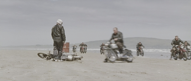 Wide shot frame from The World's Fastest Indian — standing, hat, bicycle